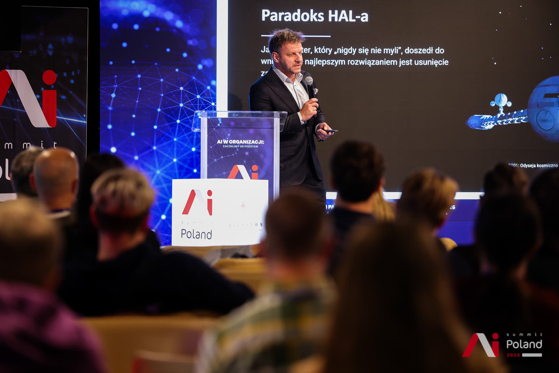 Prelegent przy mównicy podczas prezentacji o paradoksie HAL-a